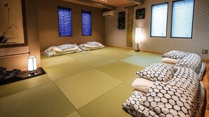 A tatami mat room with a bed, a massage table, and a lamp. - TSUDOYA Sannou (Osaka)