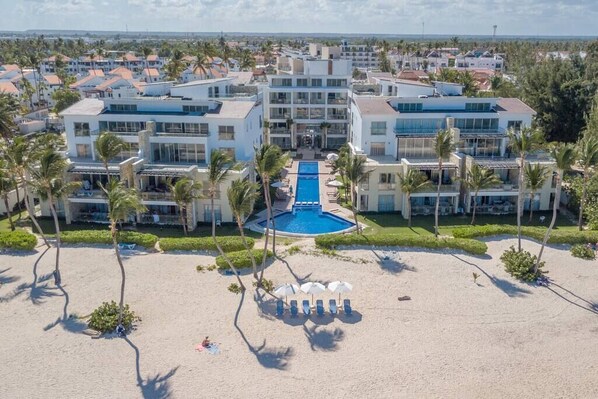 A resort with a central pool, multiple buildings, and a beach area.