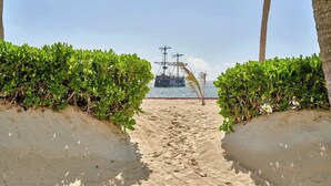 Un sentier de sable bordé de verdure qui mène à un plan d’eau.