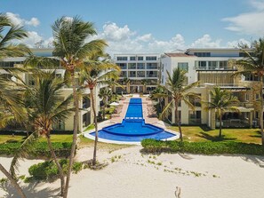 Un resort con piscina central, palmeras y edificios modernos.