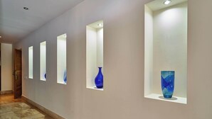 Un couloir doté d’un éclairage encastré et de vases disposés sur des étagères.