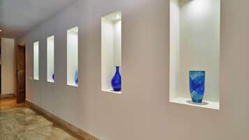 A hallway with recessed lighting and vases on shelves.