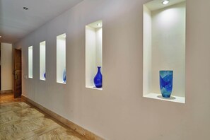 Un pasillo con iluminación empotrada y jarrones en estantes.