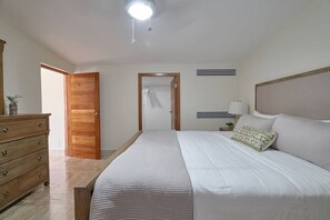 A bedroom with a bed, dresser, and a door leading to another room. - Beach Penthouse Sea View Bh-401 @Costa Atlantica (Punta Cana)