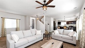 Un salon moderne avec deux canapés, une table basse et un ventilateur de plafond.