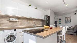 Een moderne keuken met een centraal eiland, ingebouwde apparatuur en een zithoek met een bank en kunstwerken.