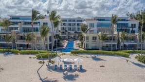 A resort with a pool, palm trees, and beach chairs. - Oceanfront Superior Condo with Pool in Punta Cana (Punta Cana)