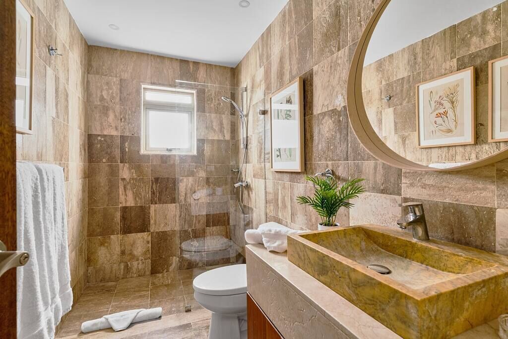 Une salle de bain avec un grand lavabo, des toilettes et un espace douche.