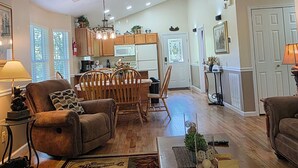 A spacious living room with a ceiling fan, wooden furniture, and a kitchen in the background. - Get Ready For Summer At Anglers Inn-1 mile from Pkwy (Pigeon Forge)