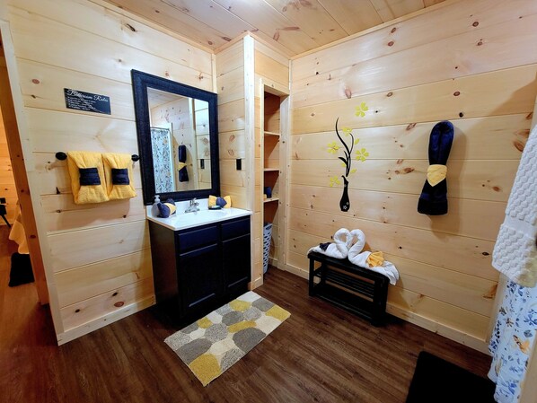 A wooden-paneled bathroom with a sink, mirror, towels, and a decorative vase. - Heavenly Daze!!! Mountain Getaway!!!! (Cosby)
