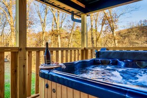 A hot tub with a wooden deck and a view of trees.