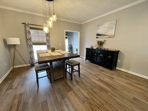 Een eetgedeelte met een houten tafel, bankjes en een kroonluchter.