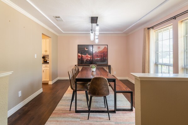A dining area with a wooden table, chairs, and a rug. There is a painting on the wall and a window with blinds. - Pool table, BBQ, pool table, fire pit, nearby golf courses (Carrollton)