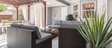 A covered patio area with wicker furniture, a ceiling fan, and a potted plant.