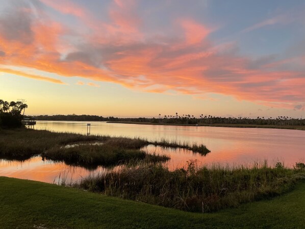A serene landscape with a calm body of water reflecting the sky, surrounded by grassy areas and a distant tree line. - Boater’s Paradise (Crystal River)