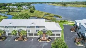 A hotel with a central building, a parking lot, and a body of water in the background. - Boater’s Paradise (Crystal River)