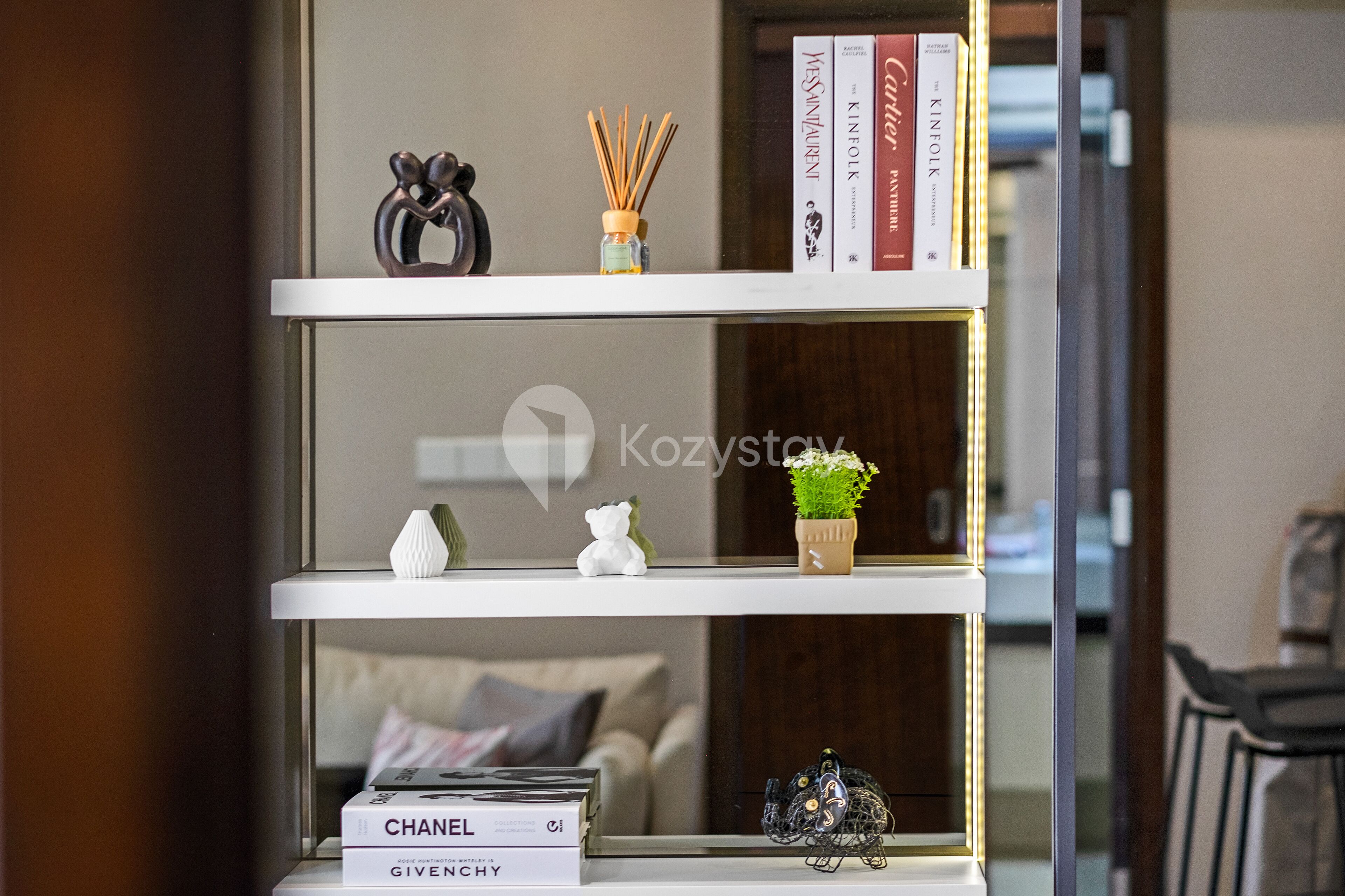A bookshelf with books, a small plant, and decorative items.