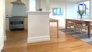 Eine geräumige Küche mit Kochinsel, Esstisch aus Holz und Stühlen.