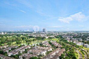 Vista aérea de uma área residencial com casas, um parque e um horizonte urbano ao longe.