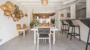 A dining area with a long table, white chairs, and a bar area with black chairs. - Villa Mahana Martinique (Les Trois-Îlets)