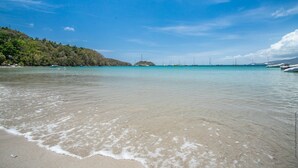 A beach with clear turquoise water, gentle waves, and a distant view of sailboats. - Villa Mahana Martinique (Les Trois-Îlets)