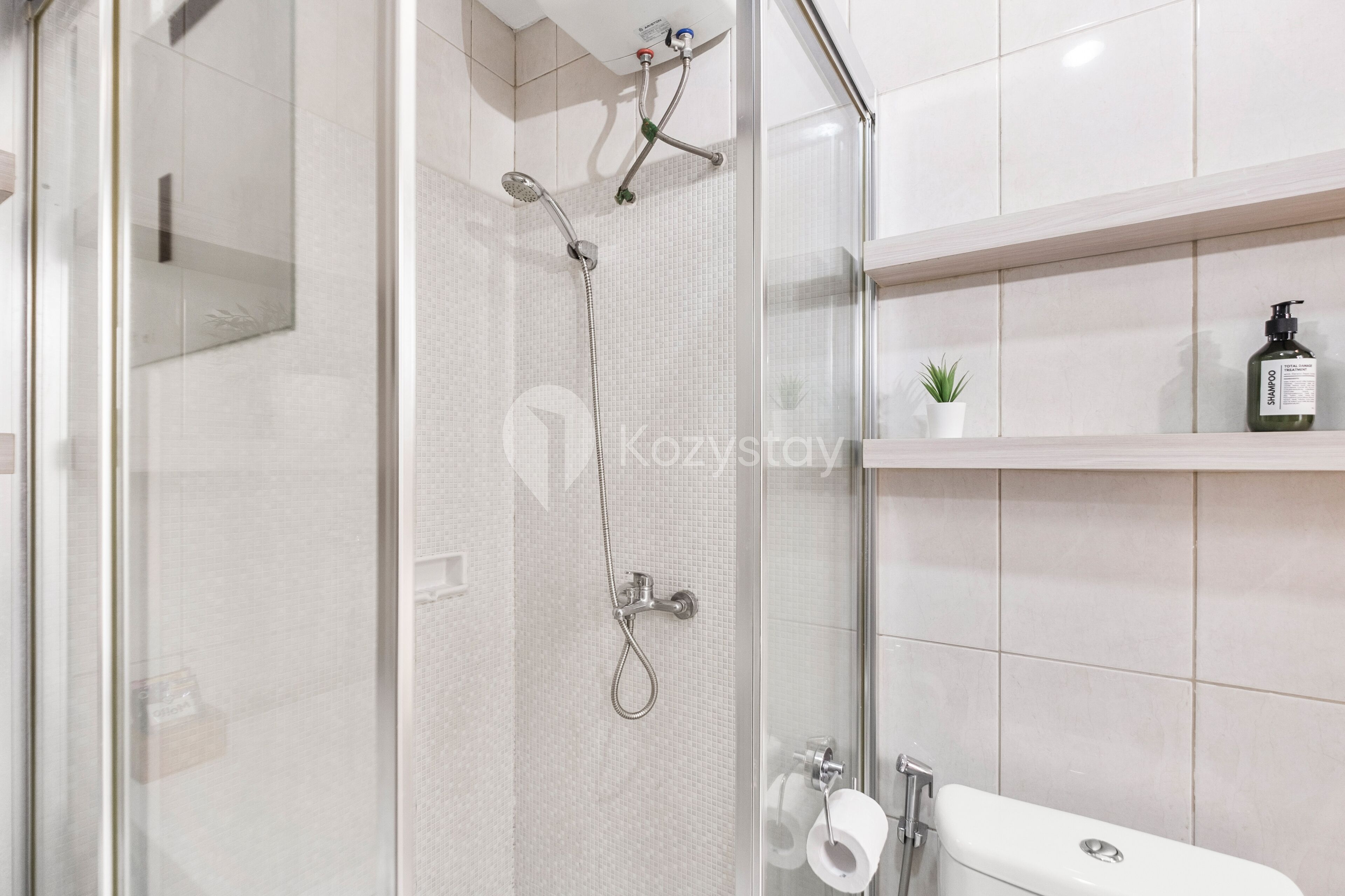 A modern bathroom with a glass shower enclosure, a toilet, and a shelf with toiletries.