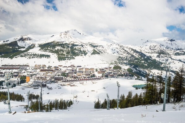 A snow-covered mountain town with buildings and ski slopes. - Il Rododendro (City Center) (Bardonecchia)