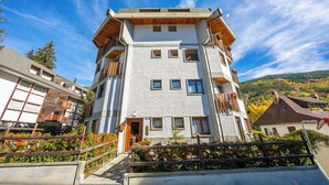 A multi-story building with balconies, a wooden staircase, and a view of the surrounding landscape. - Il Rododendro  (City Center) (Bardonecchia)