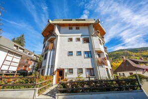 A multi-story building with balconies, a wooden staircase, and a view of the surrounding landscape.