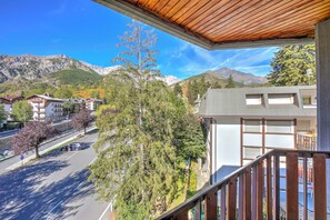 A balcony with a view of a mountain, a parking area, and buildings.