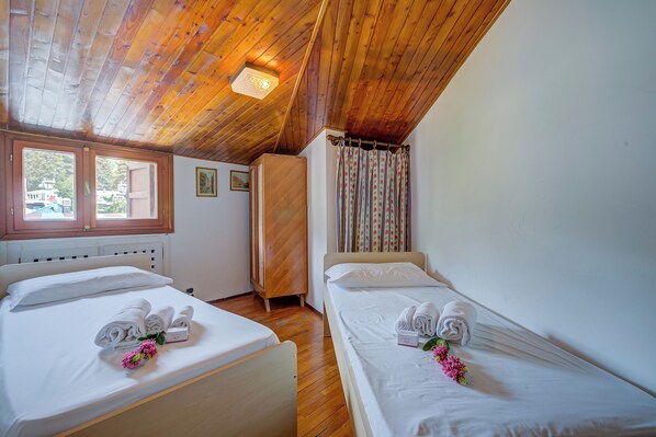 A room with two beds, wooden ceiling, and a window.