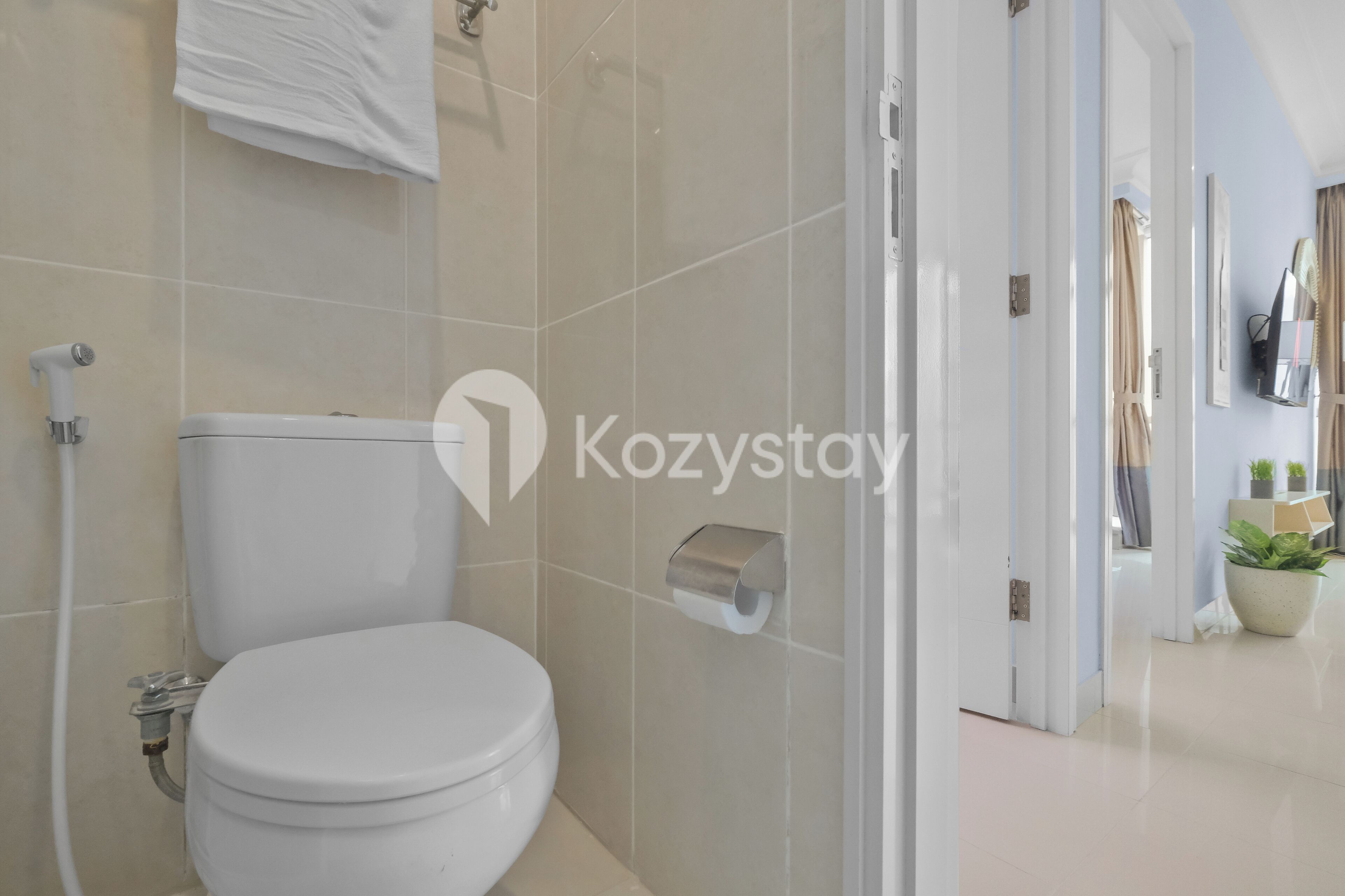 A modern bathroom with a toilet, a towel dispenser, and a shower area.