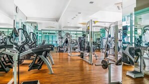 Une salle de sport équipée de machines de cardio, de matériel de musculation et de miroirs aux murs.