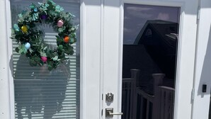 Eine weiße Tür mit Fensterglas und einem Kranz mit bunten Verzierungen.