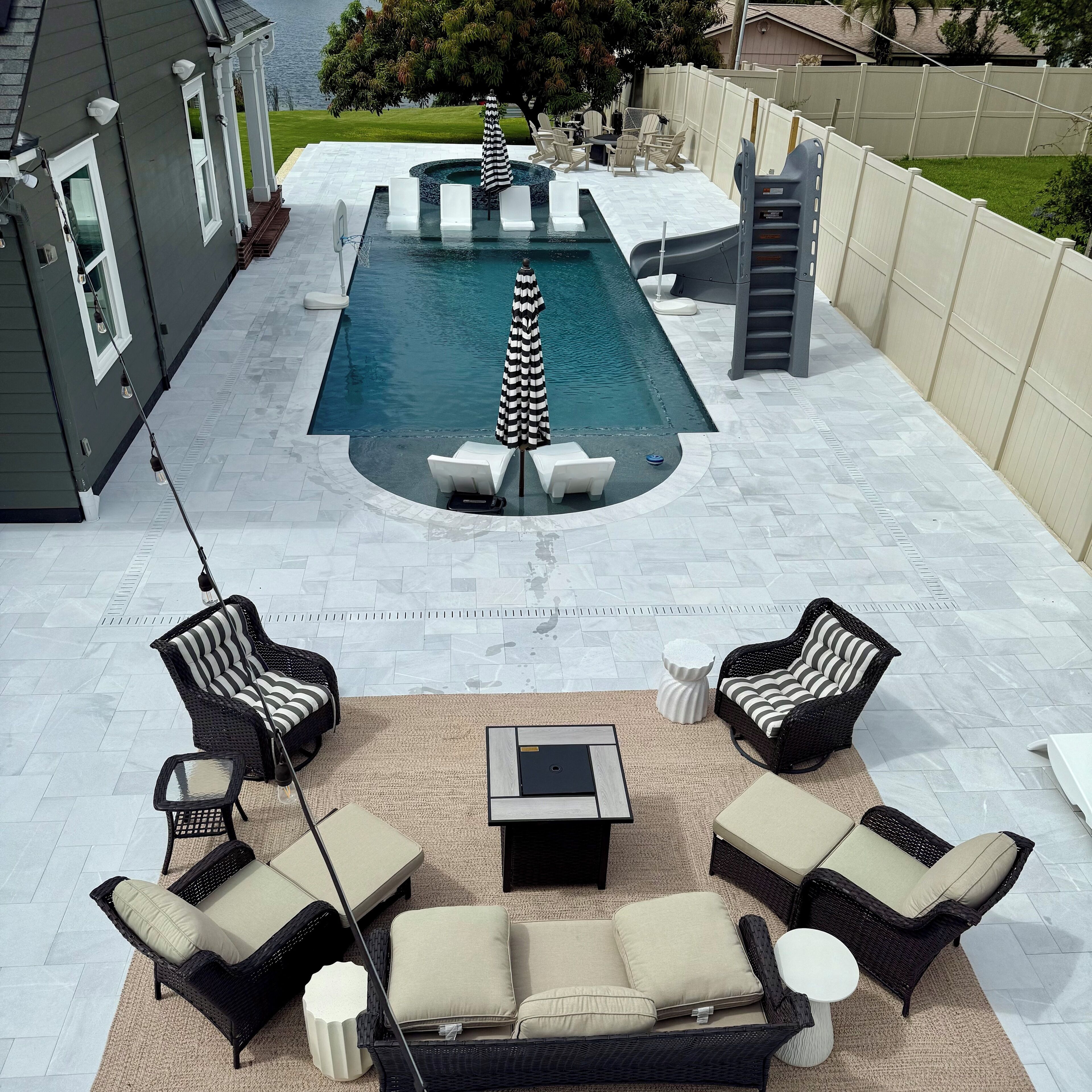Ein Garten mit Swimmingpool, Gartenmöbeln und Blick auf den Ozean.