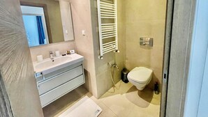 Casa de banho moderna com lavatório, espelho, porta-toalhas e sanita.