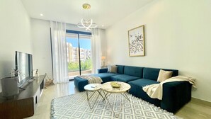 Uma sala de estar moderna com um sofá azul, uma mesa de centro redonda e um tapete estampado.