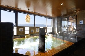 Relax in a serene hot spring bath surrounded by a mountainous landscape.
