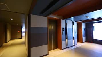A modern hotel corridor with a wooden floor, a sliding door, and a view of the outside.