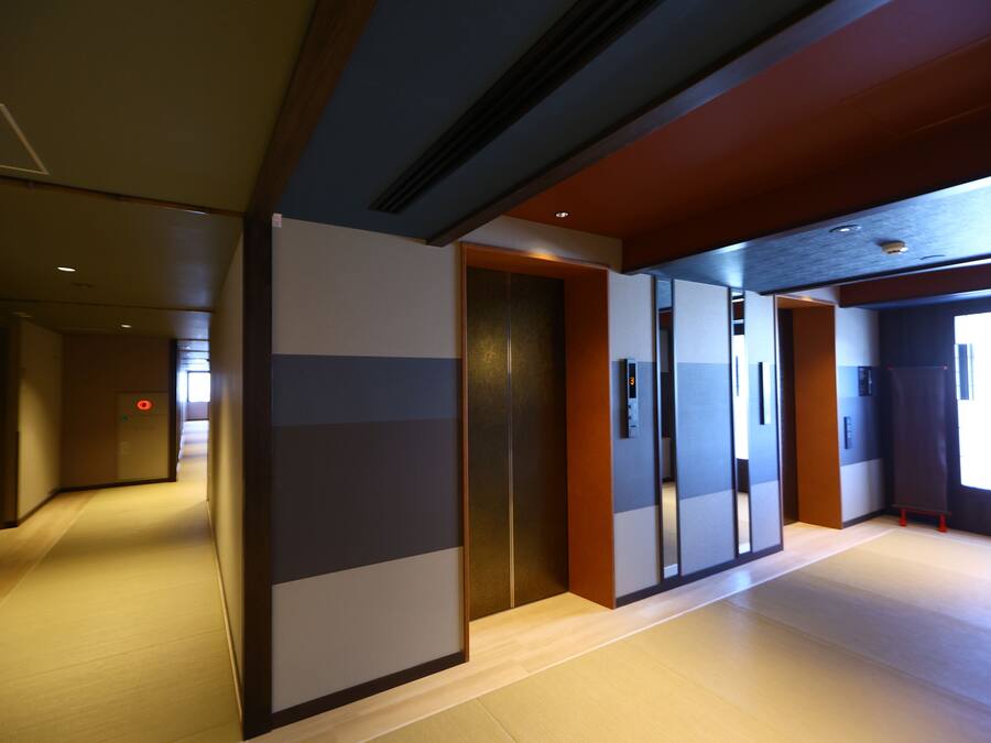 A modern hotel corridor with a wooden floor, a sliding door, and a view of the outside.