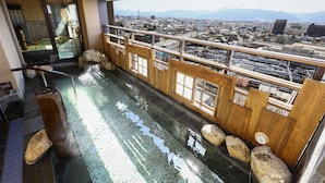 A view from a balcony with a glass barrier, overlooking a cityscape with mountains in the distance. - aduminoyu onyado nonomatsumoto (Matsumoto)