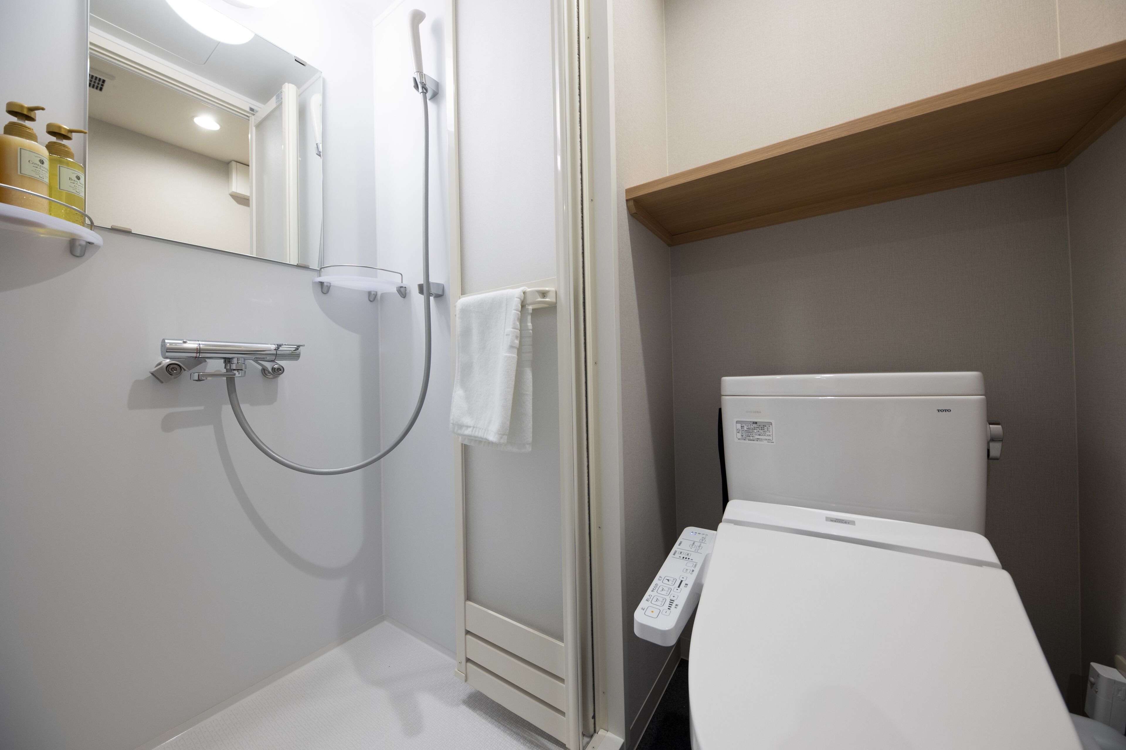 Un baño moderno con ducha, inodoro y panel de control.