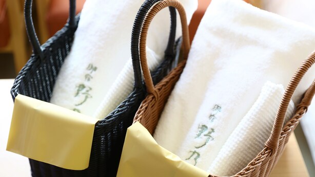 A wicker basket containing folded towels with green text.
