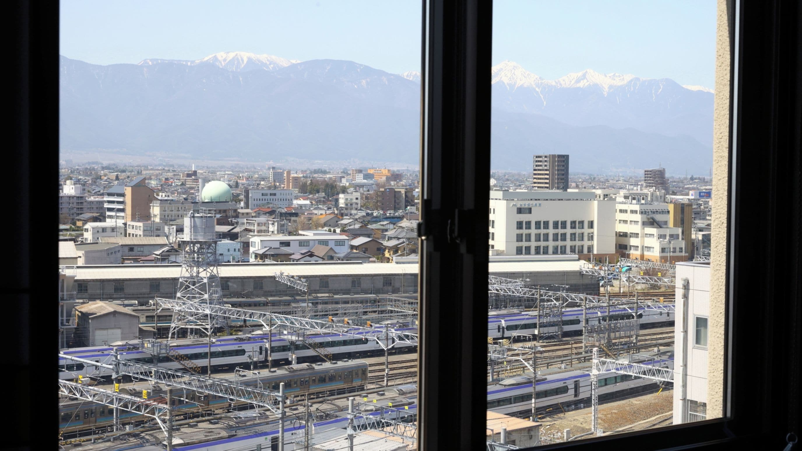 A cityscape with a train station and mountains in the background.