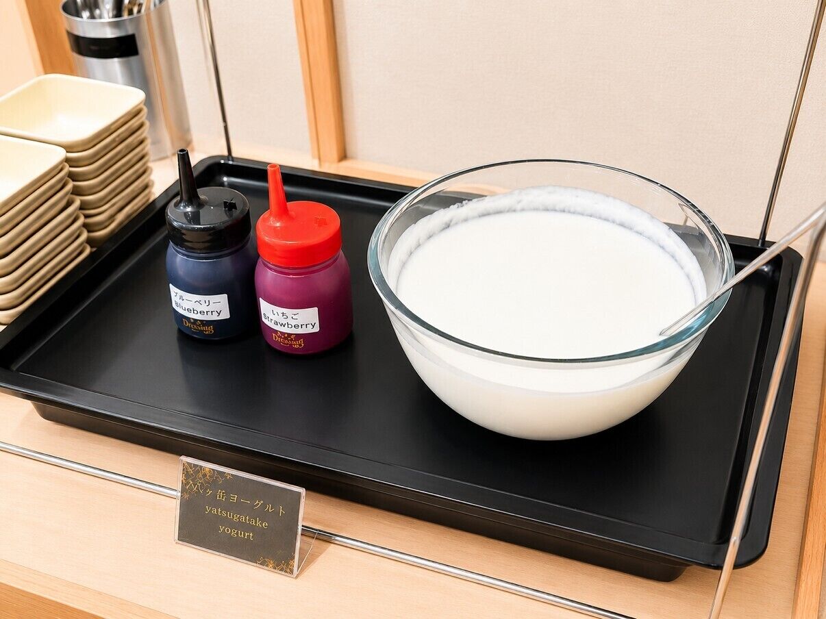 Una bandeja con un tazón de líquido blanco, dos botellas de condimentos y una pila de platos color beige.