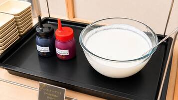 A tray with a bowl of white liquid, two condiment bottles, and a stack of beige plates.