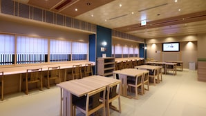 A conference room with multiple tables and chairs, a projection screen, and a television. - aduminoyu onyado nonomatsumoto (Matsumoto)