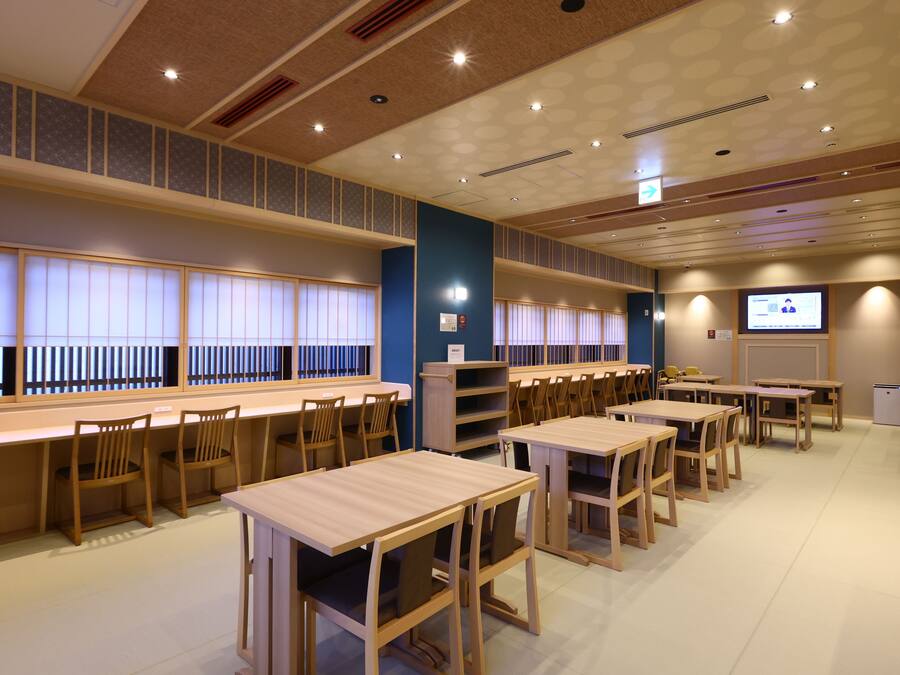 A conference room with multiple tables and chairs, a projection screen, and a television.