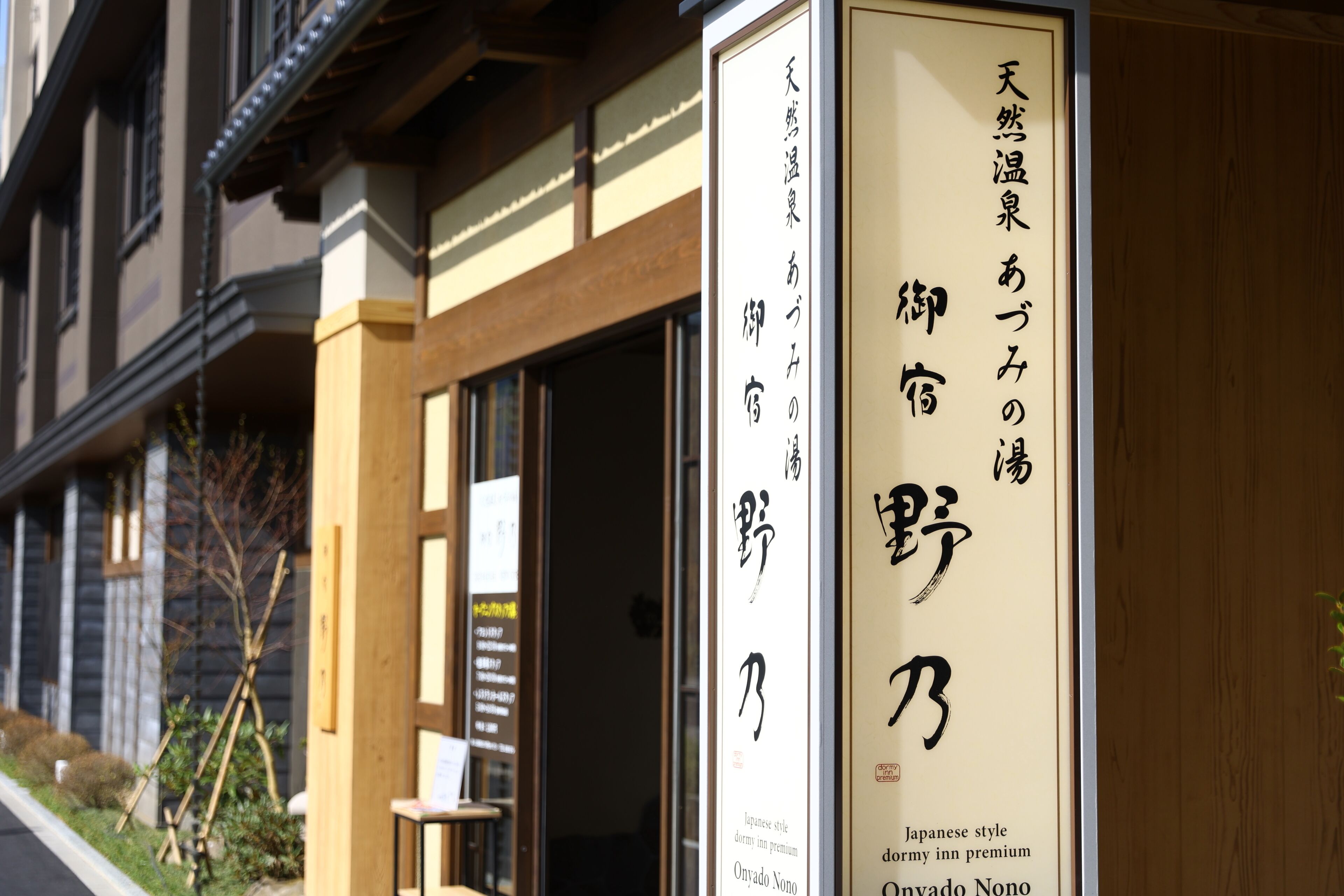 Une enseigne d’hôtel avec des caractères japonais et du texte en anglais indiquant qu’il s’agit d’une auberge de jeunesse de qualité supérieure, de style japonais.