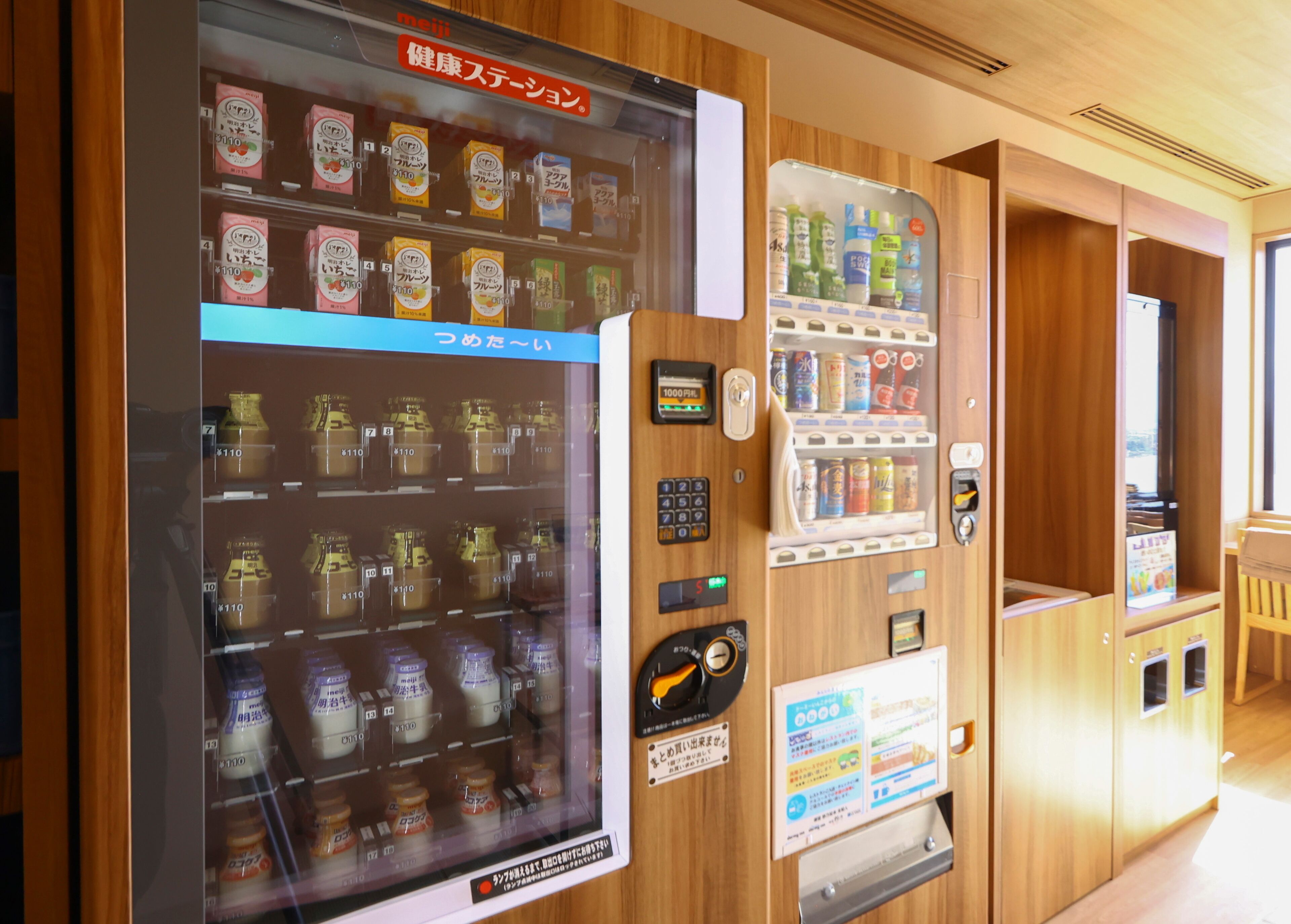 A vending machine with various beverages and snacks, a payment terminal, and a sign with information.